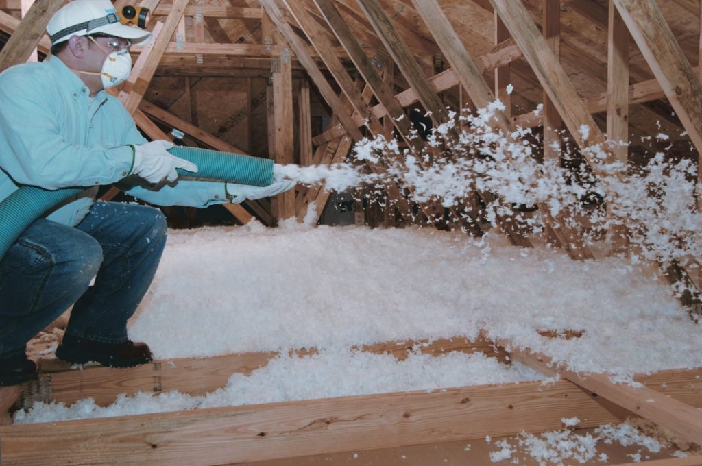 Technician installing blown-in insulation in an attic