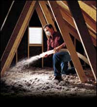 Technician installing blown-in insulation in an attic.