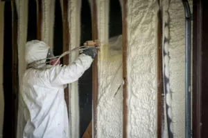 Worker spraying closed-cell spray foam insulation on a home's walls
