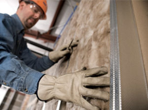 Technician removing batt insulation from a wall.